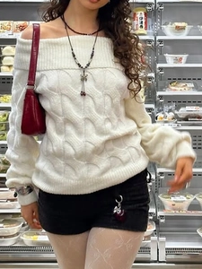 Detail of white off-the-shoulder knit sweater with cable pattern and puff sleeves
