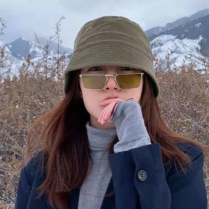 Chic gold metal square sunglasses with yellow lenses paired with a green bucket hat