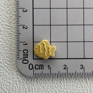 Close-up showing a 1.5cm yellow resin fish charm measured on a metric scale ruler