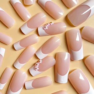 Classic French press-on nails with white tips and 3D pink floral accents on nude base