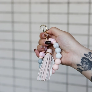 Close-up of pink marble silicone beads and leather tassel on a gold keychain wristlet