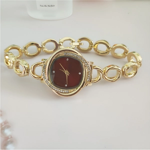 Detailed macro view of a gold flower-shaped watch with red dial and crystal-set bezel