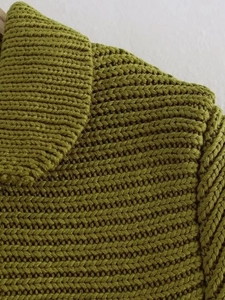 Detail of chunky olive green knit sweater showing collar seam and heavy knit texture