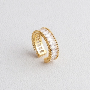 Detail of adjustable gold ring with rectangular zircons and beaded edge on white texture