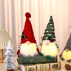 Nahaufnahme von gemütlich leuchtenden Weihnachtswichteln mit Strickmützen und Deko