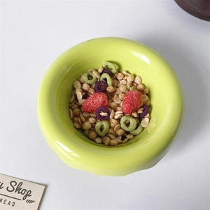 Top view of a light green ceramic cereal bowl filled with granola and dried strawberries