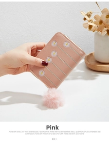Detailed view of pink leather coin purse with daisy embroidery and plush ball pendant