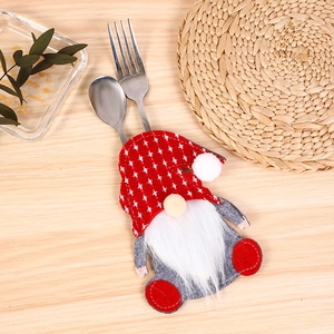 Detail of Christmas gnome cutlery holder with fork and spoon on wooden table background