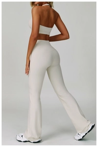 Back view of white cross-back yoga bra and high-waist flared pants set on model
