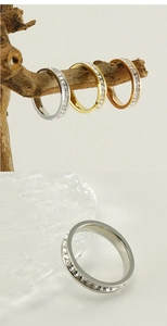 Detail of three stackable stainless steel eternity rings in silver, gold, and rose gold