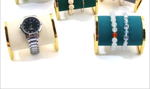 Golden metal watch display stand with velvet cylinders showing bracelets in detail