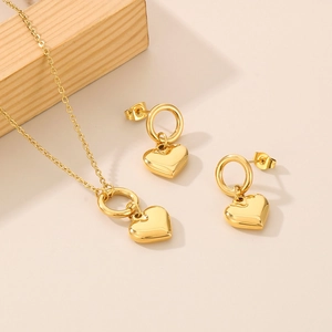 Detail shot of the golden heart-shaped necklace and earring set with a polished finish