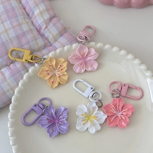 Nahaufnahme bunter Kirschblüten-Schlüsselanhänger auf einem weißen Keramikteller