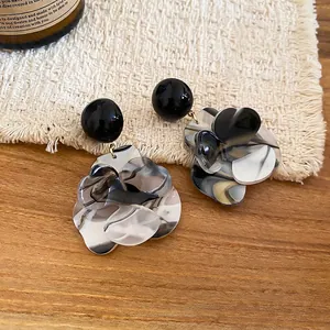 Boucles d'oreilles fleurs en résine à motif marbré avec clous noirs sur fond de bois