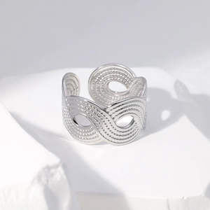 Detail of silver wavy texture open ring on white geometric stone with sleek metallic finish