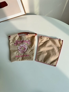 Detail of beige nylon tote and zipper pouch with pink Sweet embroidery