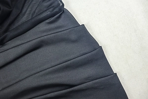 Dettaglio di raso nero arricciato con inserto in mesh velato e pieghe multistrato