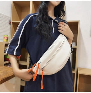 Detail of white waterproof chest bag featuring vibrant orange zipper pulls and wide strap