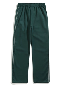 Detail view of dark green woven joggers with side stripes and elastic waist
