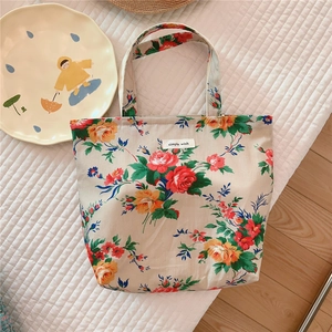 Detail of floral cotton tote bag with a small woven label on a white quilted background