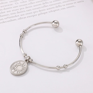 Détail du pendentif soleil et lune sur un bracelet jonc ouvert en acier inoxydable poli