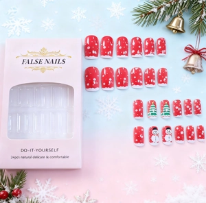 Close-up of Christmas themed press-on nails with snowman and tree patterns in a pink box