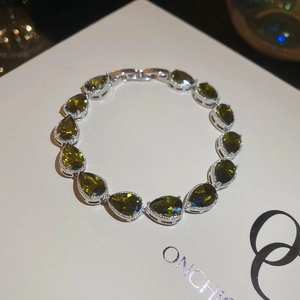 Detail of silver-tone bracelet featuring pear-cut olive green stones and claw settings