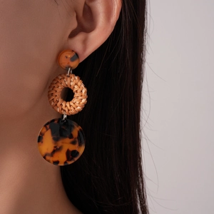 Detail of bohemian resin and rattan drop earrings on model with macro texture