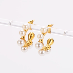 Macro view of C-shaped gold-plated earrings featuring inlaid white pearls and metal frame