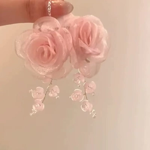 Close-up of pink resin rose earrings with glitter details and beaded flower tassels