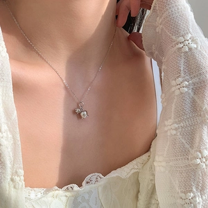 Detail of silver puppy pendant necklace worn by a model showcasing minimalist style