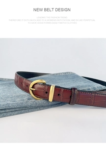 Detail of reddish-brown crocodile pattern leather belt with golden D-shaped buckle on jeans