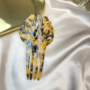 Detail of tortoise shell acetate hair comb with leaf patterns on beige silk fabric