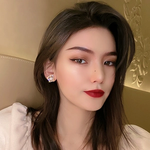 Elegant gold flower earrings with pearls and crystals worn by a model in soft lighting