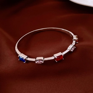 Detail of silver bangle with vibrant multi-colored gemstones on dark silk background