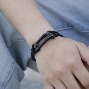 Detail of black braided leather bracelet for men featuring a metallic U-shaped clasp