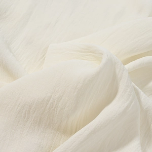 Detailed macro view of cream-colored textured fabric with elegant natural pleated folds