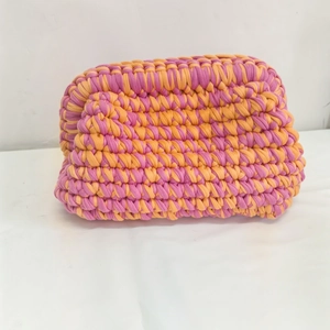 Pink and orange handmade crochet clutch bag with thick knit texture and cloud-like shape