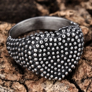 Vintage stainless steel heart ring with textured bead surface on rustic wood background