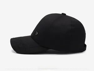 Détail de casquette noire montrant la broderie montagne 318 et le logo bouclier métal