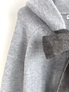 Detailed close-up of grey knitted hoodie texture with dark grey bow knot accents