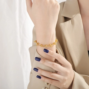 Macro view of gold knot design chain bracelet on woman's wrist with minimalist office style