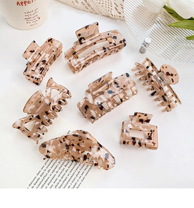 Collection of seven large tortoiseshell hair claws in leopard print on a clean white surface