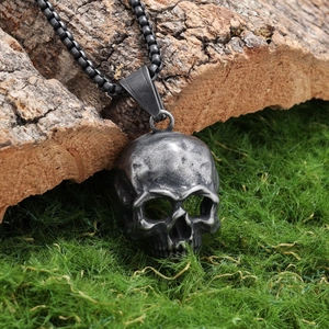 Retro stainless steel skull pendant necklace with box chain on natural wood background