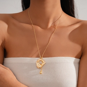 Detail of minimalist gold irregular geometric pendant necklace worn on a model's neck