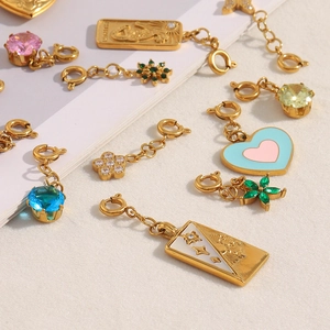Detailed close-up of 18K gold-plated heart and geometric pendants with colorful gemstones