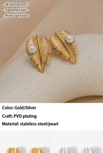 Détail de boucles d'oreilles feuille en acier PVD avec perle et texture en métal brossé