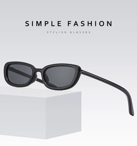 Detail view of black oval sunglasses with dark gray lenses on a white geometric stand
