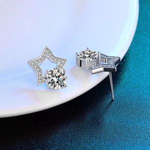 Macro detail of D-color moissanite star earrings on white ceramic and blue background