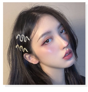 Close-up of gold and silver snake-shaped hairpins with rhinestones on a model